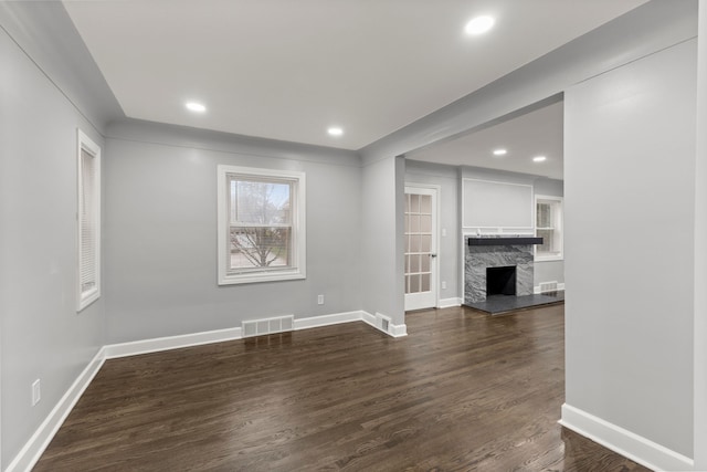 unfurnished living room featuring dark wood-style floors, a fireplace, recessed lighting, visible vents, and baseboards