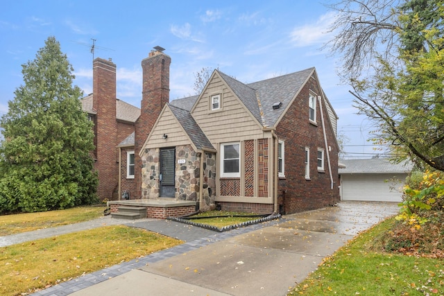 view of front of home featuring an outbuilding, brick siding, a shingled roof, stone siding, and a front lawn