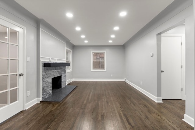 unfurnished living room with recessed lighting, dark wood-style flooring, a fireplace, and baseboards