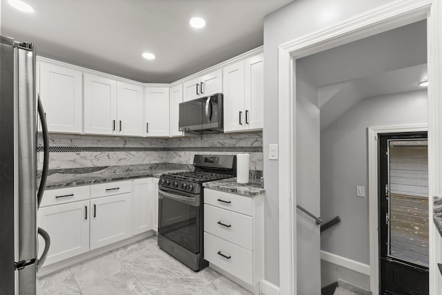 kitchen with dark stone counters, stainless steel appliances, backsplash, and white cabinetry