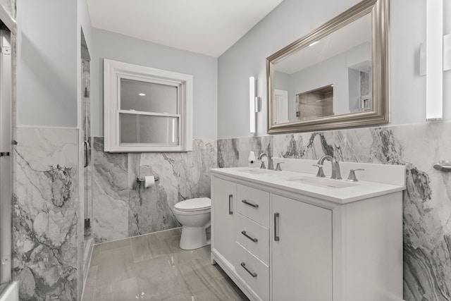 full bath featuring toilet, a wainscoted wall, double vanity, and a sink