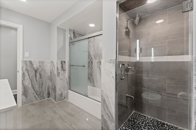 full bathroom with combined bath / shower with glass door and tile walls