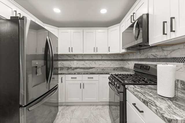 kitchen with stainless steel appliances, stone countertops, backsplash, and white cabinets