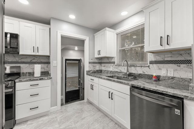 kitchen with stone countertops, white cabinets, appliances with stainless steel finishes, marble finish floor, and a sink