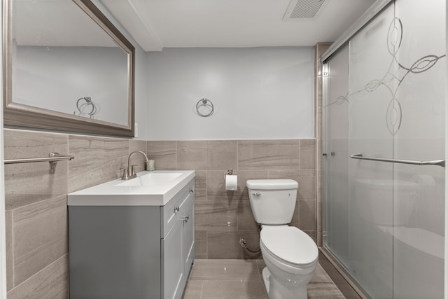 full bathroom with toilet, visible vents, vanity, tile walls, and a stall shower