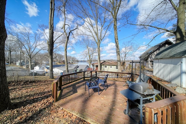 wooden terrace with a grill, a residential view, fence, and an outbuilding