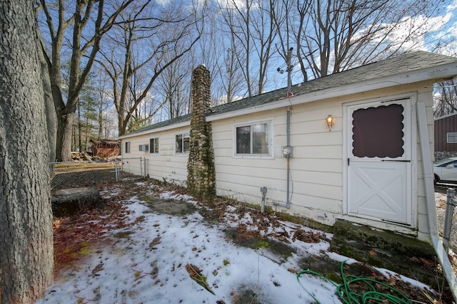 view of snow covered exterior with fence and a chimney