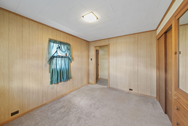 carpeted spare room featuring wooden walls and baseboards