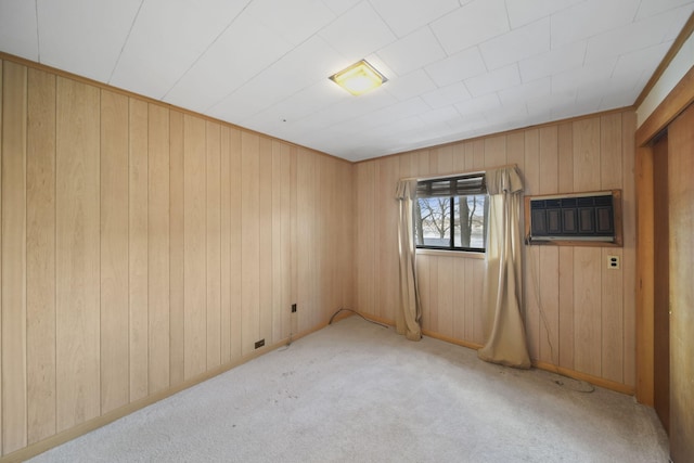 unfurnished room with an AC wall unit, light colored carpet, and wood walls