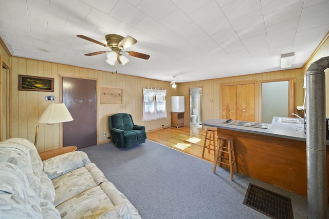 living area with carpet, visible vents, and ceiling fan