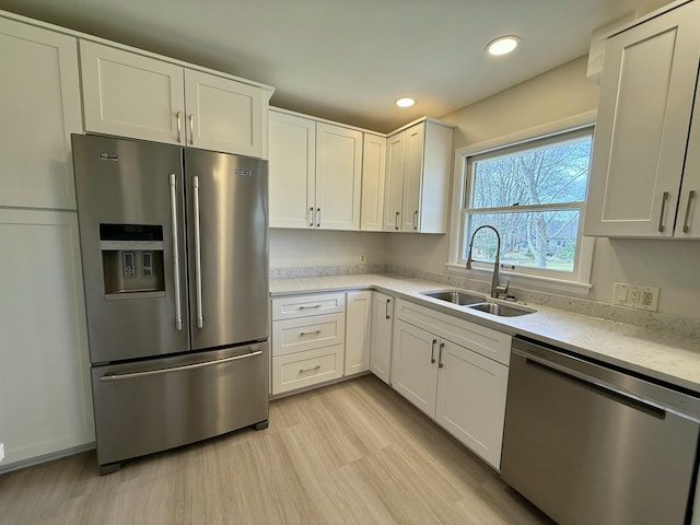 kitchen with recessed lighting, a sink, white cabinetry, light wood-style floors, and appliances with stainless steel finishes