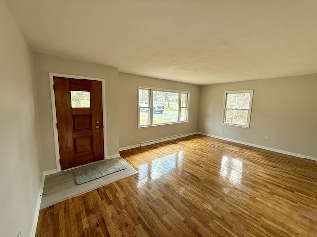 foyer entrance with baseboards, baseboard heating, and wood finished floors