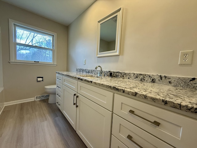 bathroom with toilet, wood finished floors, visible vents, vanity, and baseboards