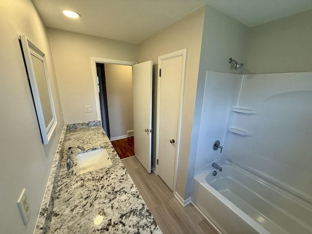 bathroom featuring double vanity, a sink, wood finished floors,  shower combination, and baseboards