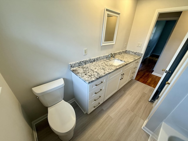 bathroom with vanity, wood finished floors, toilet, and baseboards