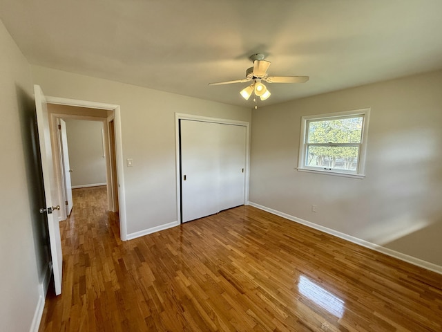 unfurnished bedroom with a ceiling fan, a closet, baseboards, and wood finished floors