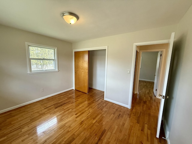 unfurnished bedroom featuring a closet, wood finished floors, and baseboards