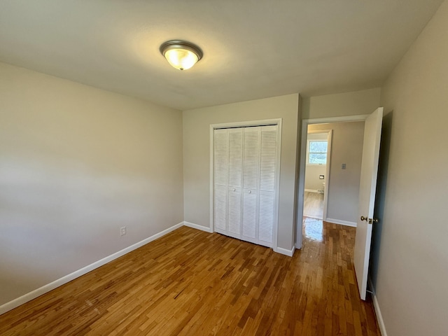 unfurnished bedroom featuring a closet, baseboards, and wood finished floors