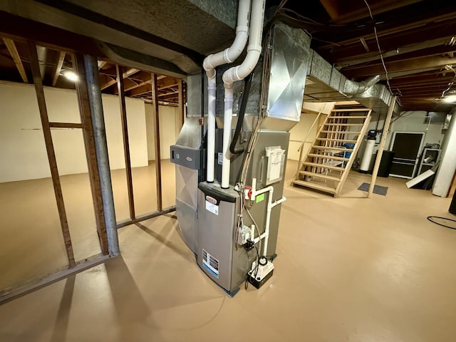 unfinished below grade area featuring heating unit and stairway