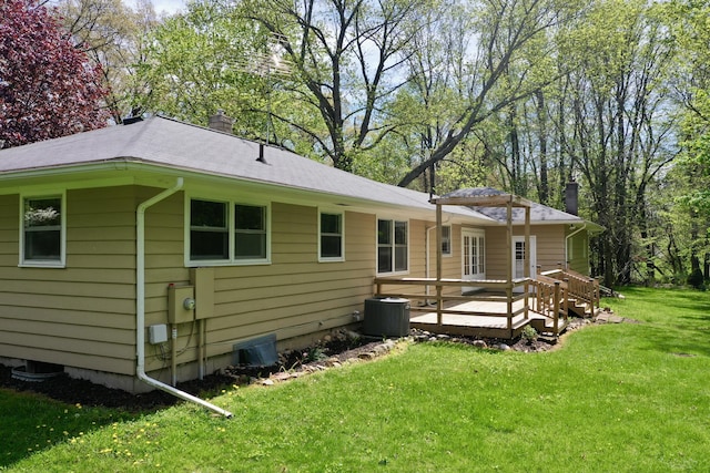 back of property with central AC, a deck, a lawn, and a chimney