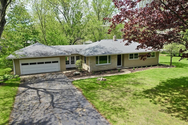 ranch-style home featuring asphalt driveway, a garage, a front yard, and roof with shingles