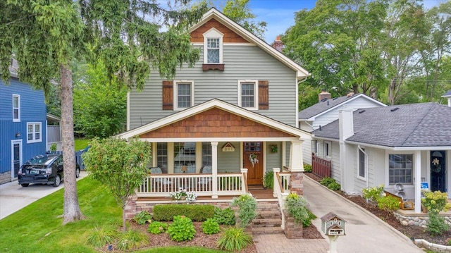 view of front of property with a chimney, a front lawn, a porch, and concrete driveway