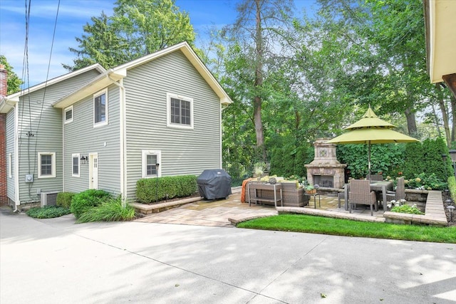 view of home's exterior with a patio, an outdoor living space with a fireplace, and central AC unit