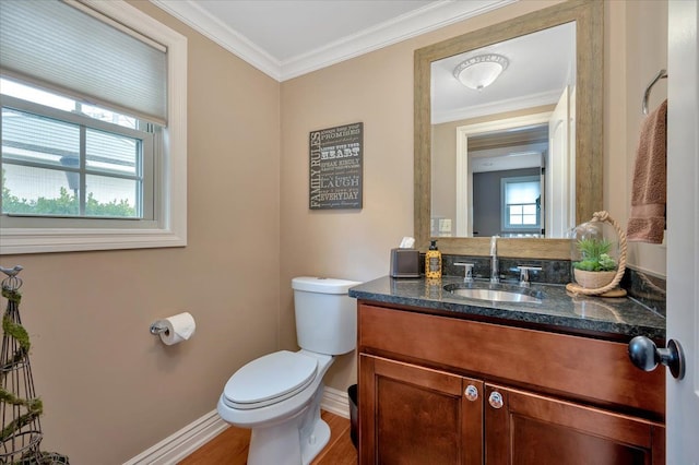 half bathroom with toilet, wood finished floors, vanity, baseboards, and ornamental molding