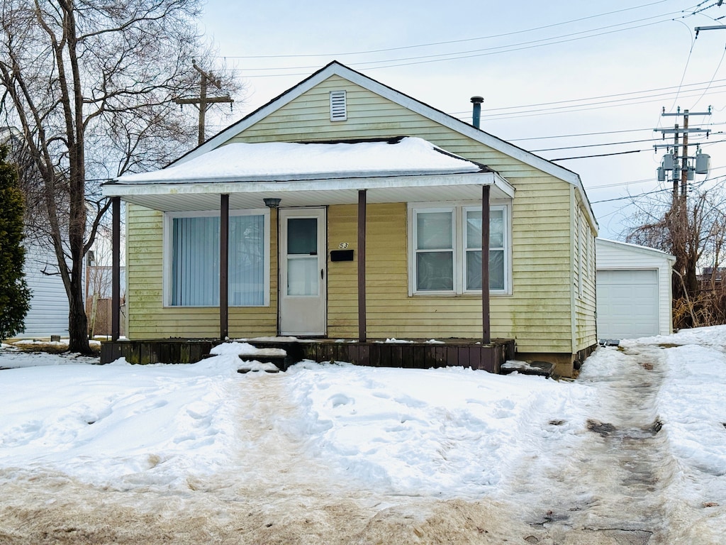 view of front facade with an outbuilding, covered porch, and a detached garage