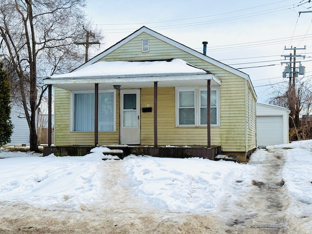 view of front facade with an outbuilding, covered porch, and a detached garage