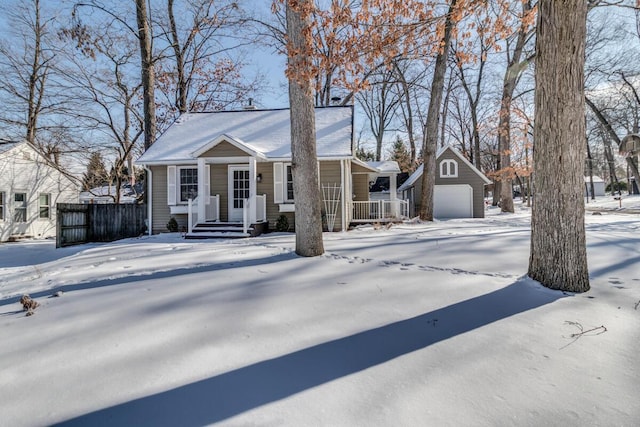 view of front of house featuring an attached garage, covered porch, an outdoor structure, fence, and driveway