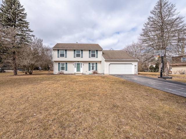 colonial home featuring driveway, an attached garage, and a front yard