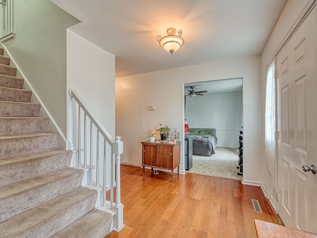 entryway with baseboards, stairs, visible vents, and wood finished floors