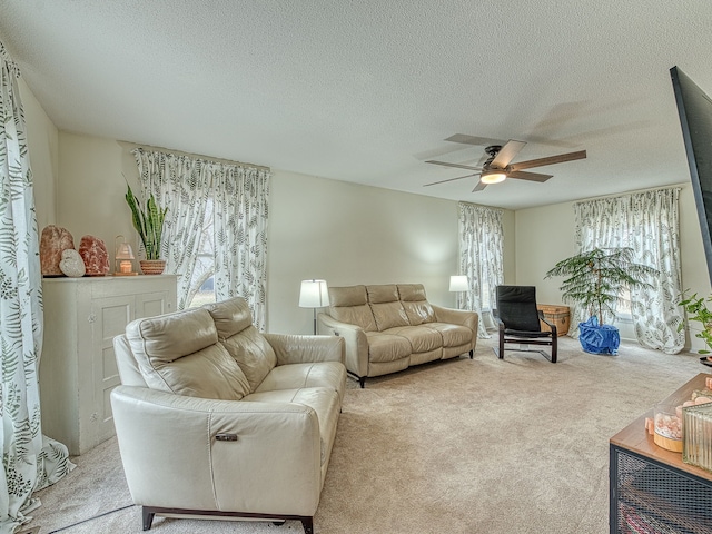 living area featuring light carpet, ceiling fan, and a textured ceiling