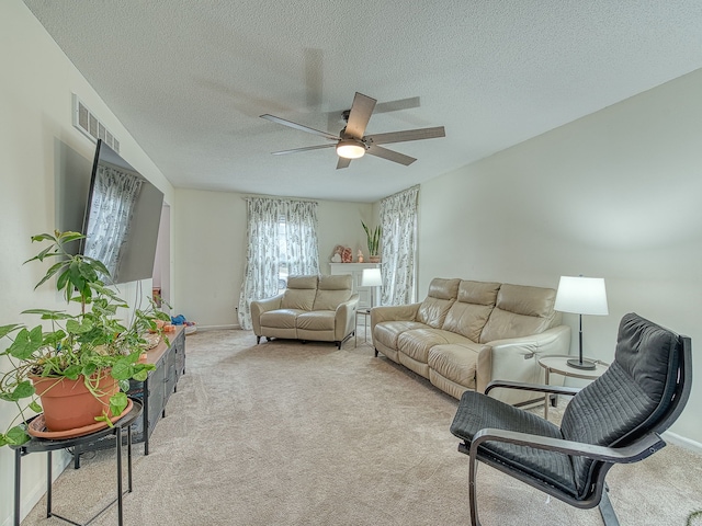 living room with a textured ceiling, carpet flooring, visible vents, baseboards, and a ceiling fan