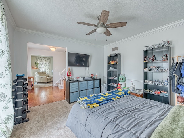 carpeted bedroom featuring a ceiling fan, visible vents, a textured ceiling, and ornamental molding