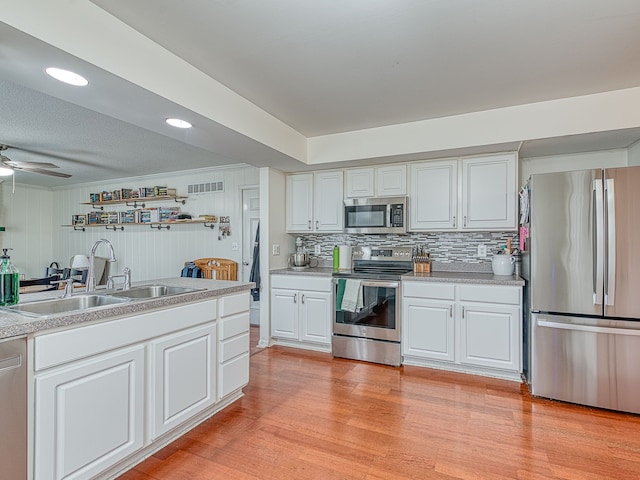 kitchen with light wood finished floors, visible vents, appliances with stainless steel finishes, light countertops, and a sink