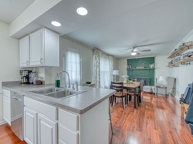 kitchen featuring light wood-type flooring, white cabinets, a sink, and dishwasher