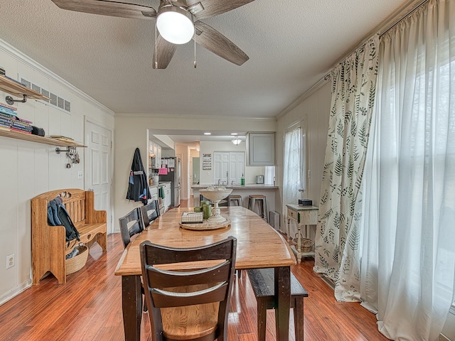 dining room featuring ornamental molding, light wood-style flooring, and a ceiling fan