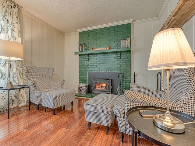 sitting room featuring ornamental molding, a brick fireplace, a textured ceiling, and wood finished floors