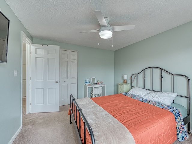 bedroom featuring light carpet, a textured ceiling, a ceiling fan, and a closet