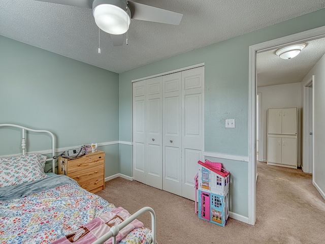 carpeted bedroom featuring a textured ceiling, ceiling fan, a closet, and baseboards