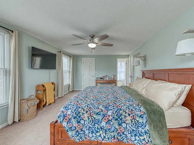 bedroom with ceiling fan, a textured ceiling, baseboards, and light colored carpet