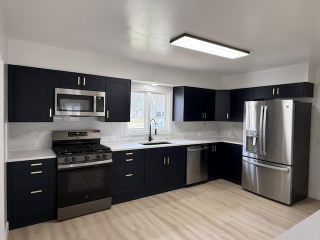 kitchen with stainless steel appliances, dark cabinetry, and a sink