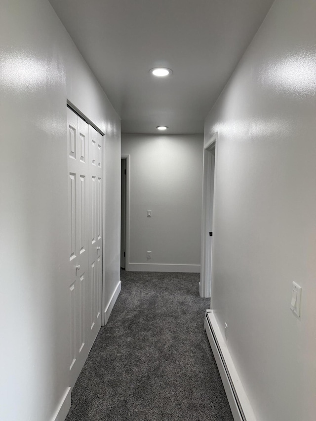 hallway featuring a baseboard heating unit, baseboards, dark colored carpet, and recessed lighting