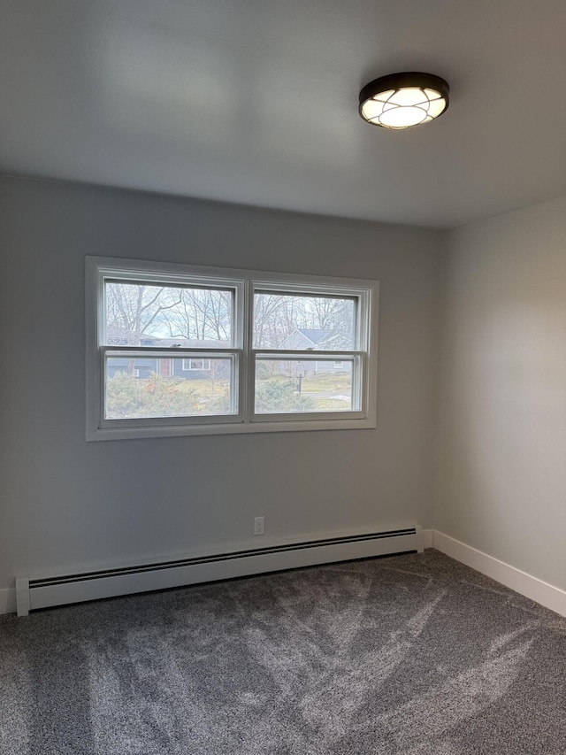 carpeted empty room featuring a healthy amount of sunlight, baseboards, and a baseboard heating unit