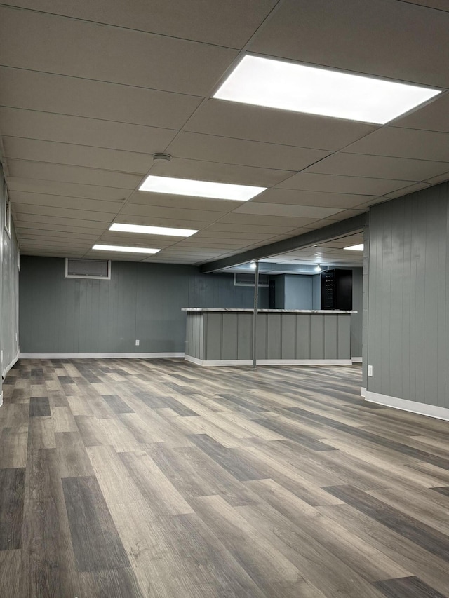 finished basement featuring a drop ceiling, baseboards, and wood finished floors