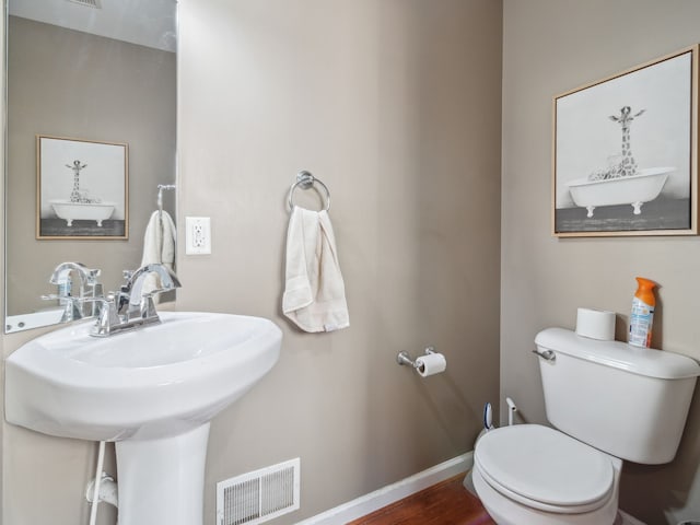 bathroom with baseboards, visible vents, toilet, wood finished floors, and a sink