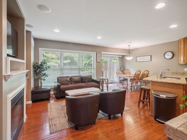 living room with recessed lighting, a glass covered fireplace, and light wood-style floors