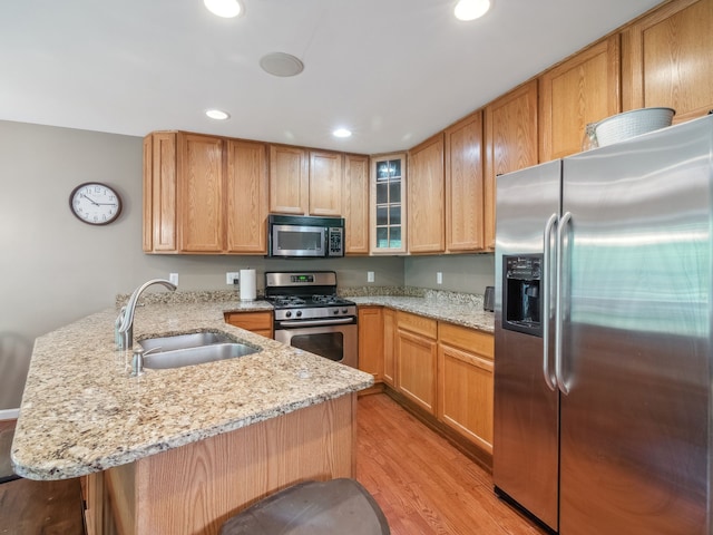 kitchen featuring a peninsula, stainless steel appliances, light wood-type flooring, a sink, and recessed lighting